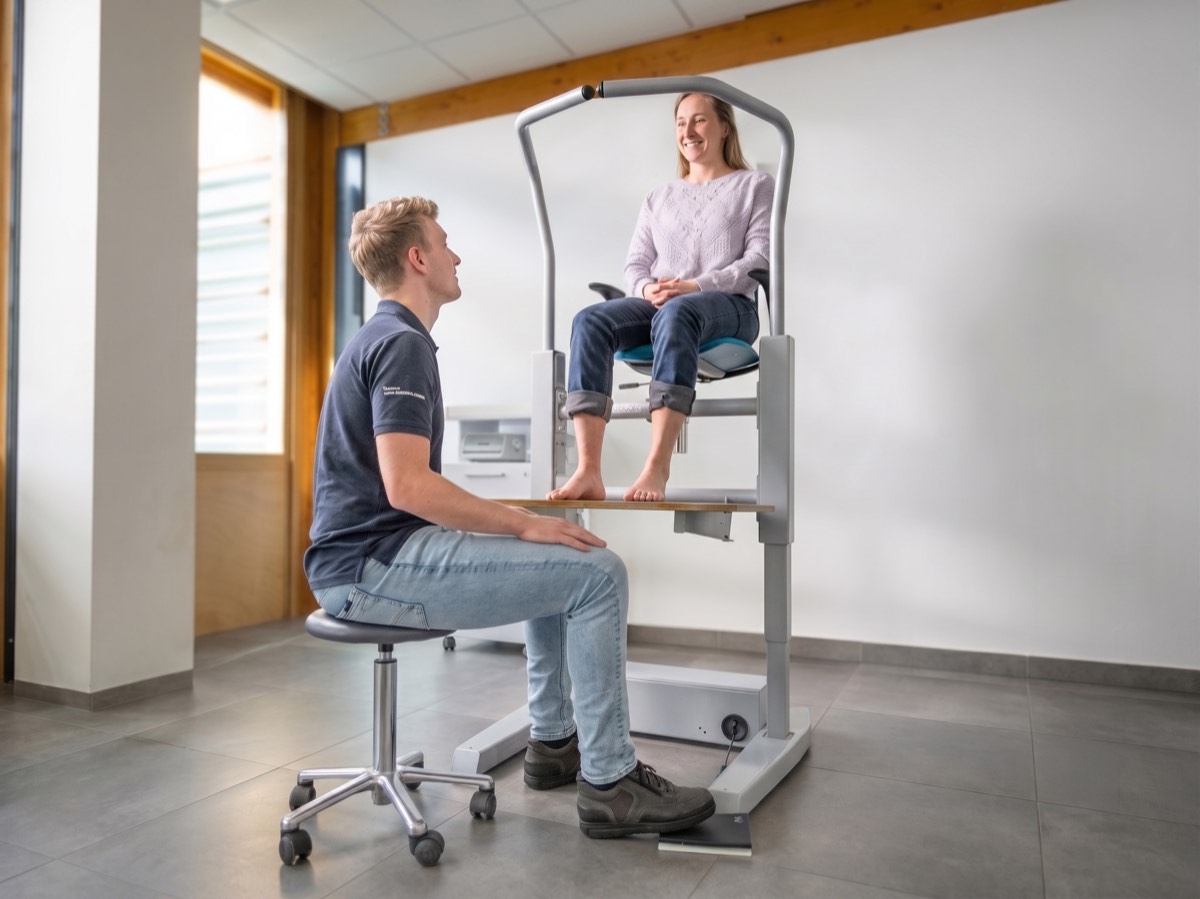 De specialist gaat op een kruk zitten met de benen onder het geheven platform.