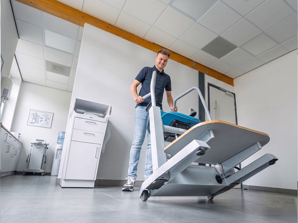 De Orthostand wordt op zijn wielen over de vloer naar een ander deel van de ruimte gereden.